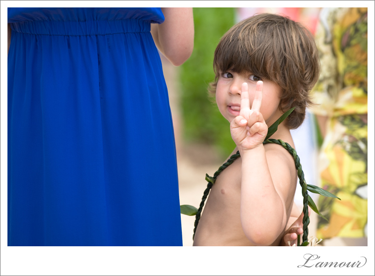 Hawaii wedding ringbearer in lei gives  the peace sign to photographers