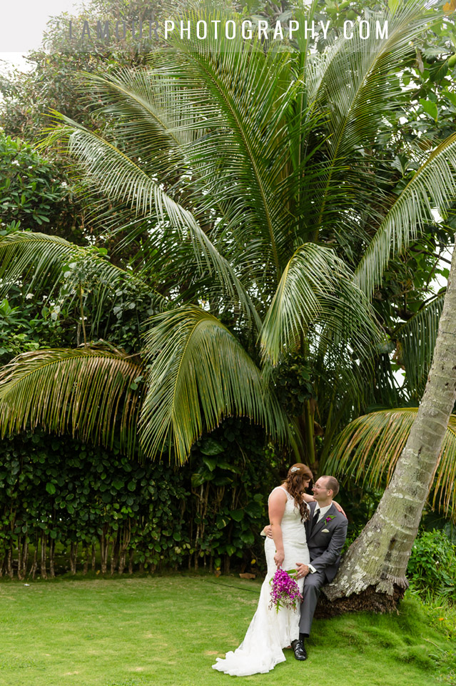 Hawaii destination wedding couple sitting on a palm tree at their reception on Oahu