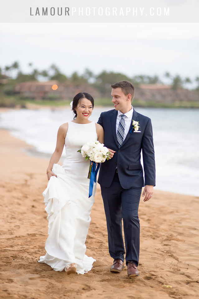 Bride and groom walk along the beach in Maui after their wedding ceremony while taking photos with the photo and video team from L'Amour