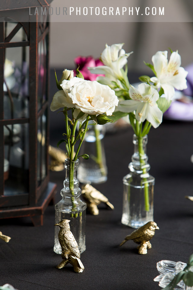 Small vases decorate a black, purple and gold wedding reception table in Hawaii