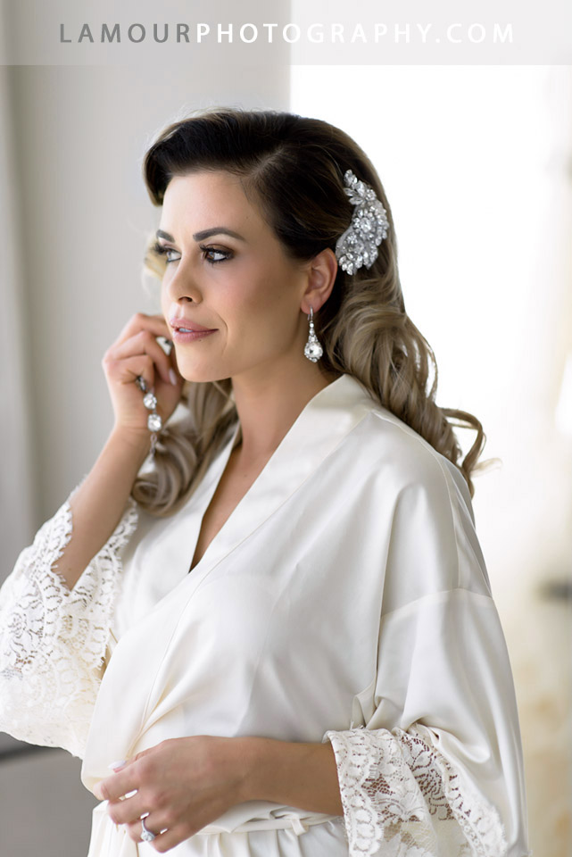 Bride in silk robe puts on earrings before putting on her dress for her Honolulu Wedding