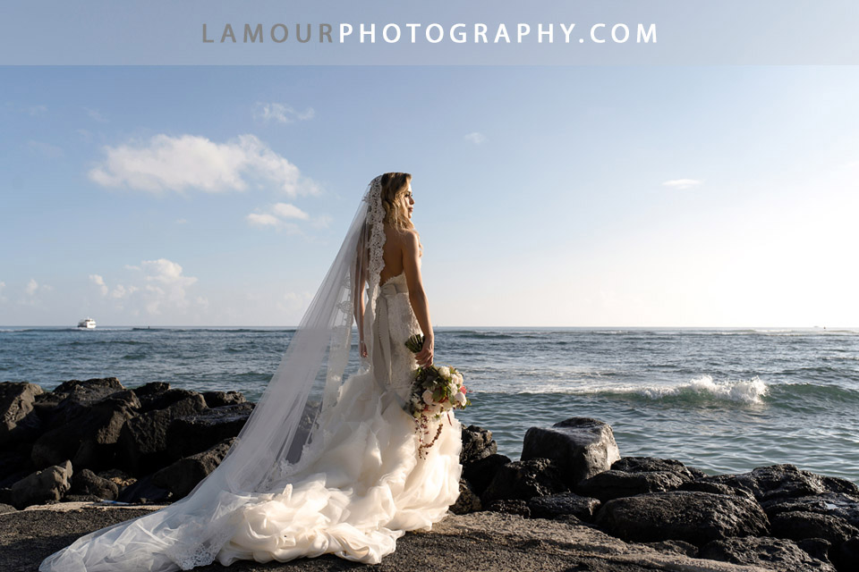 Bride in Hawaii wears strapless lace dress with sweetheart neckline and mermaid train along with a a long lace trim veil for her Wedding in Hawaii