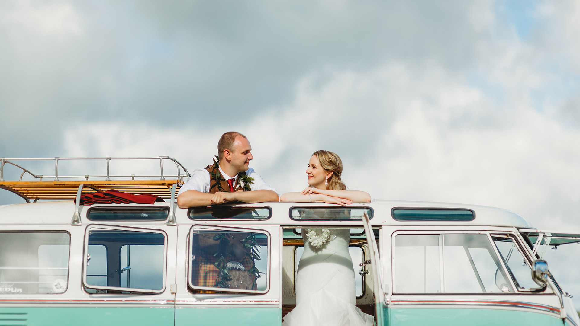A wedding couple sharing a look through the open roof of a vintage Volkswagen bus