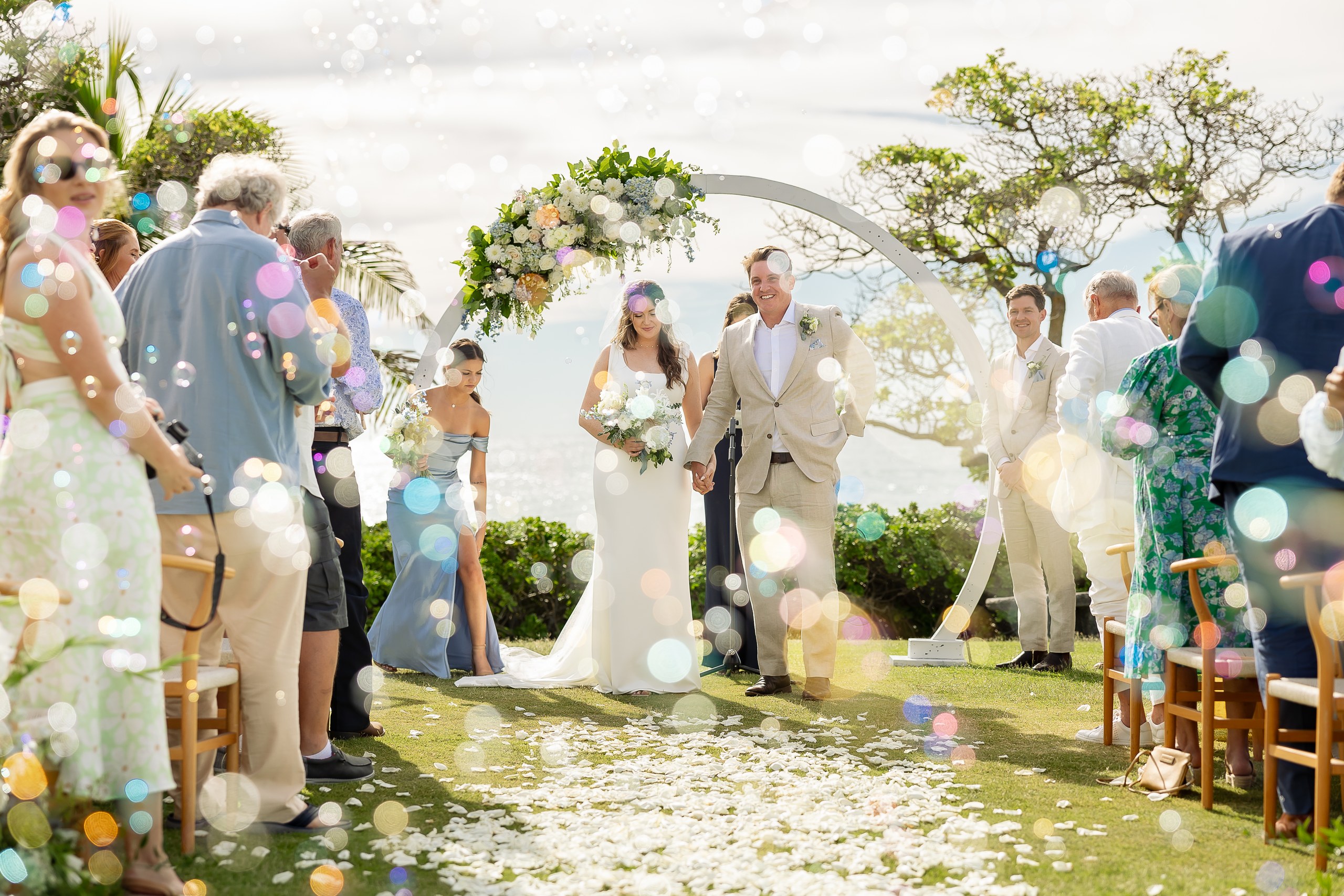 Newlyweds walking through bubbles and smiling wedding guests