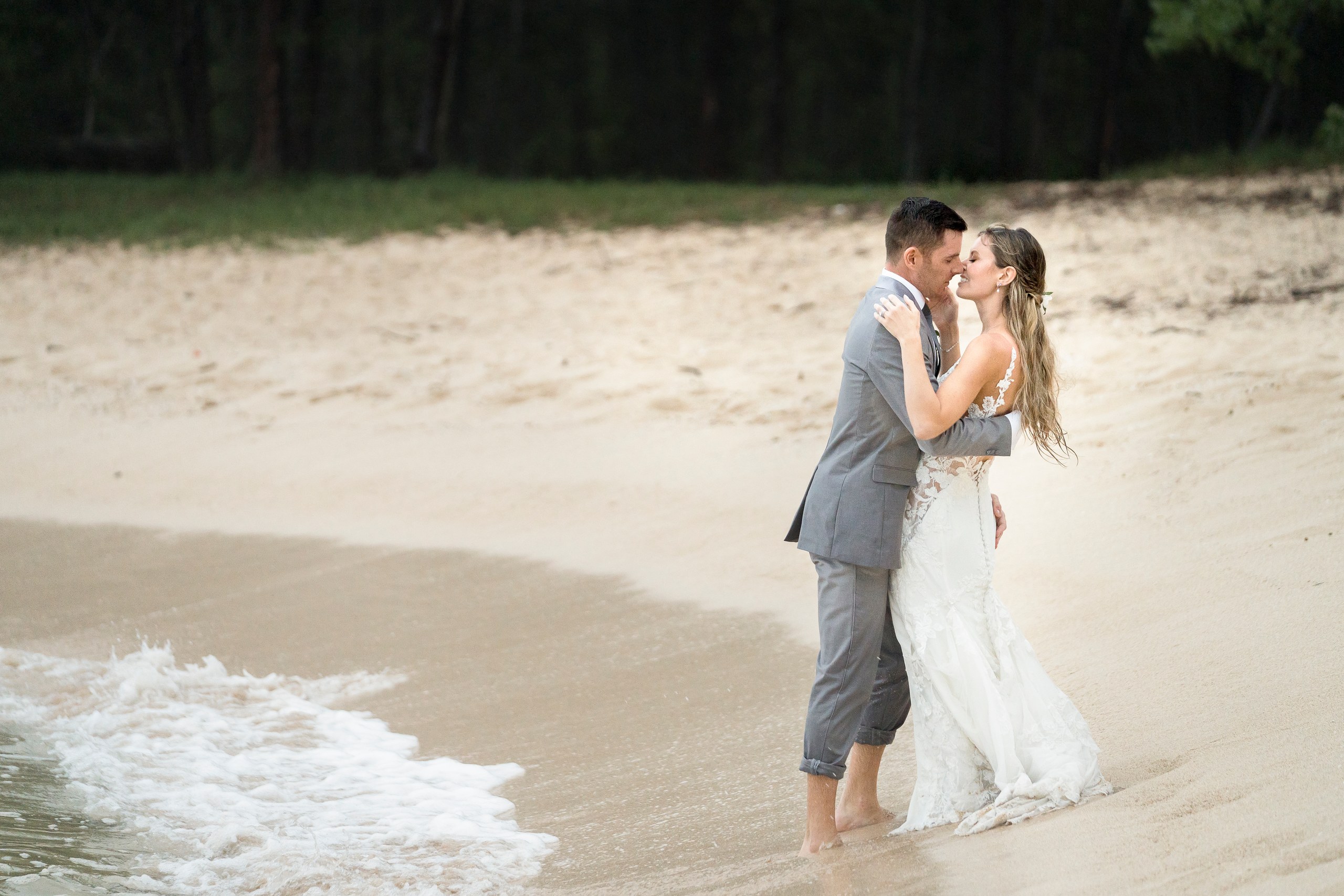 Newlyweds kissing at the edge of the water